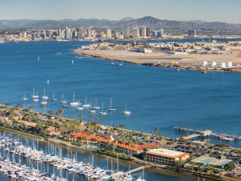 Aerial view of Shelter Island with hotels, boats in a marina, and San Diego in the distance