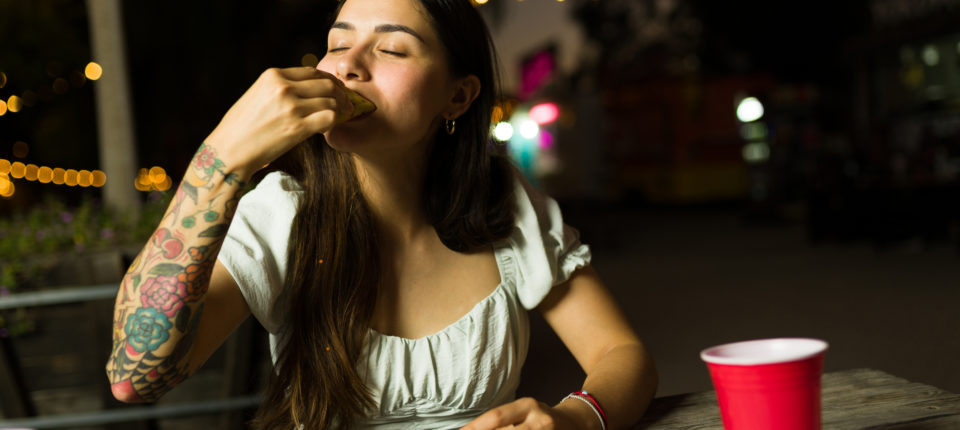Hungry mexican woman eating delicious tacos