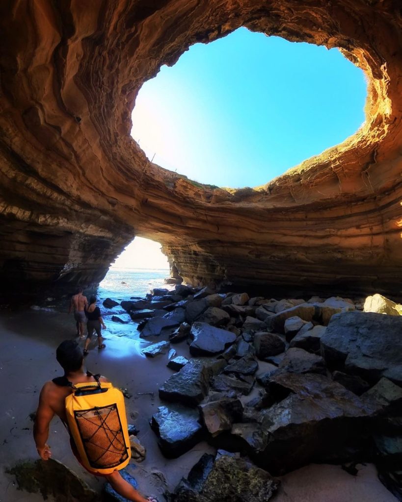 Man standing in cliff tunnel at beach