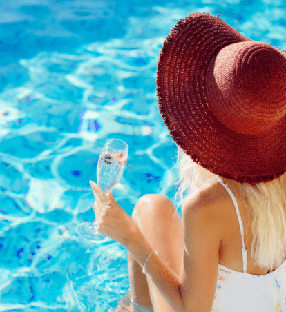 a woman sitting by the pool in a red sunhat