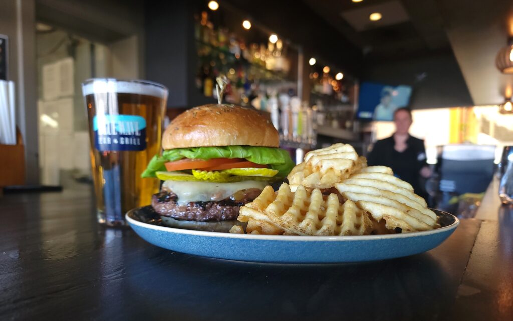a burger and waffle fries with a beer