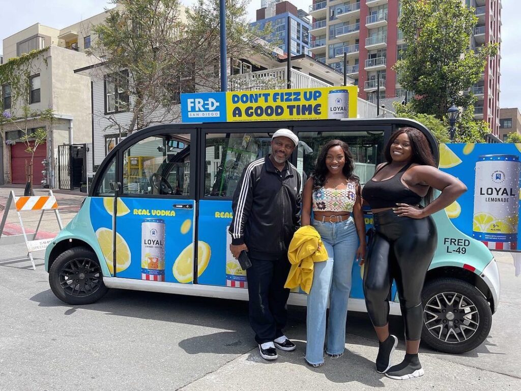 three people standing next to a FRED shuttle