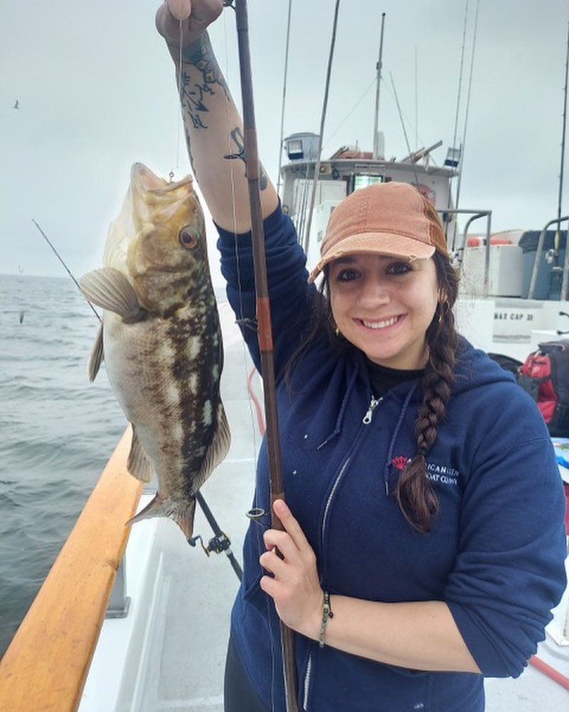 young woman on a fishing boat holding up her catch