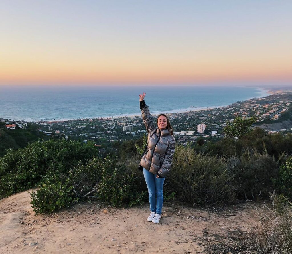 woman standing on top of a mountain overlooking the ocean