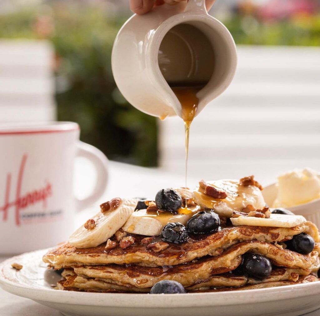 pouring syrup onto blueberry pancakes