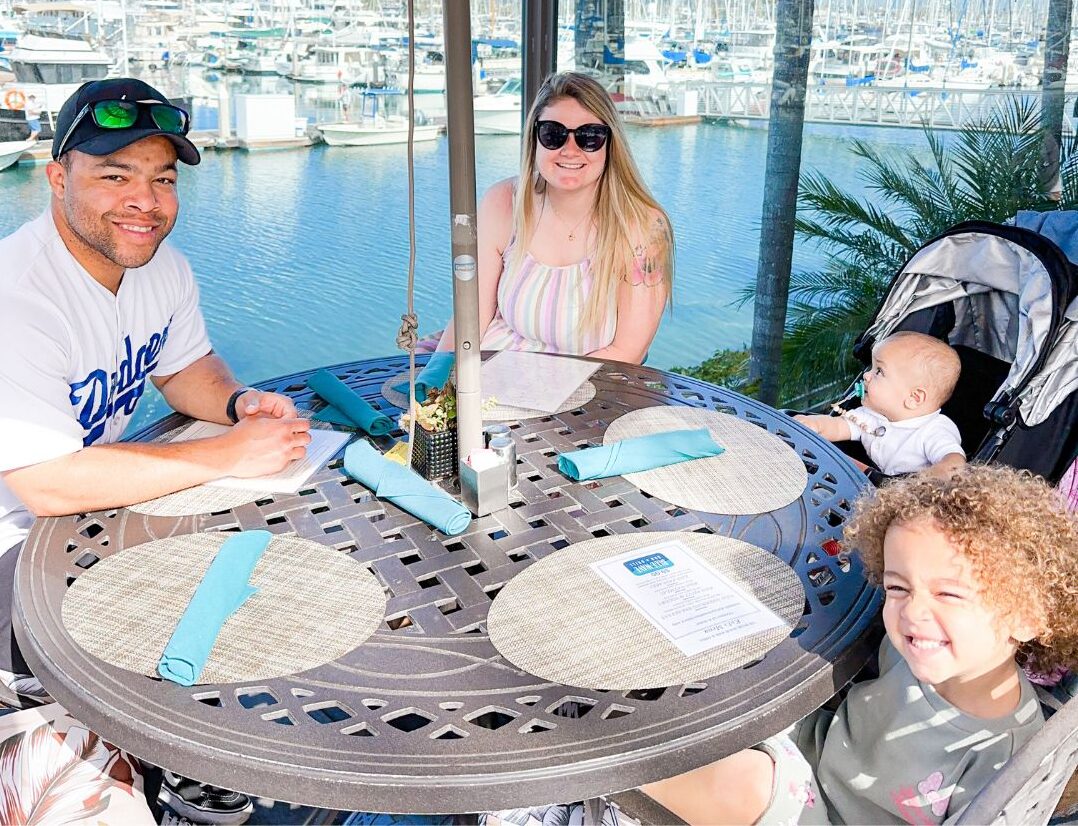 Family sitting at table in front of marina during San Diego Kids Free Month