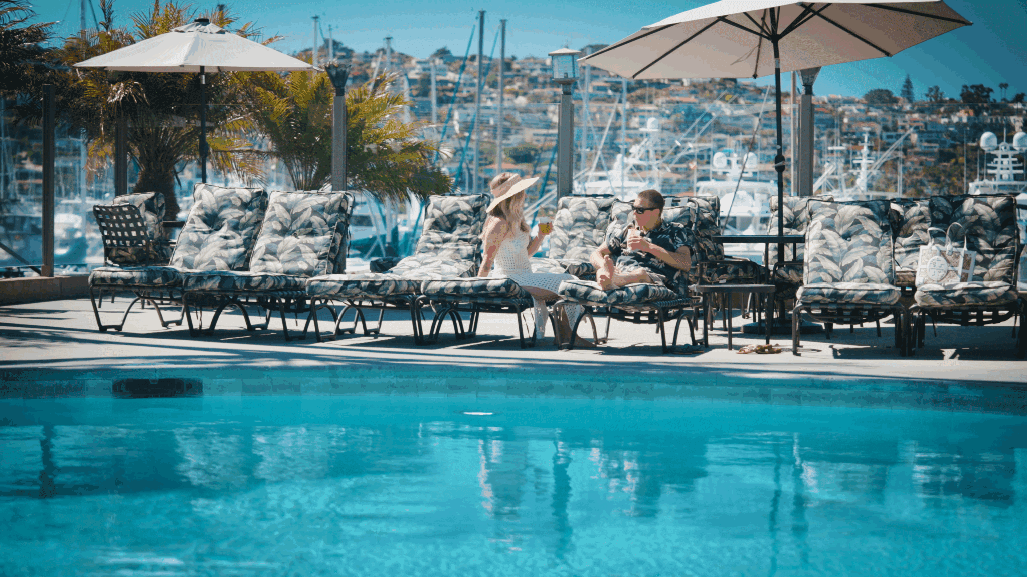 Two guests enjoying drinks next to the pool
