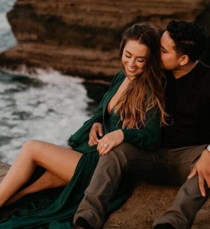 a couple reclining on the cliffs over the water
