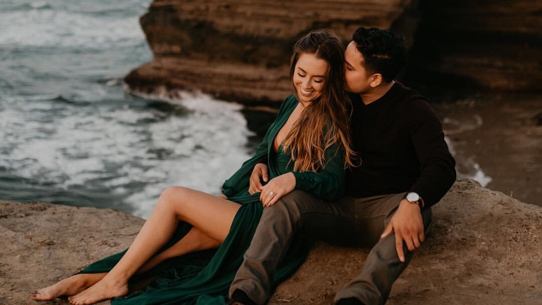 a couple reclining on the cliffs over the water