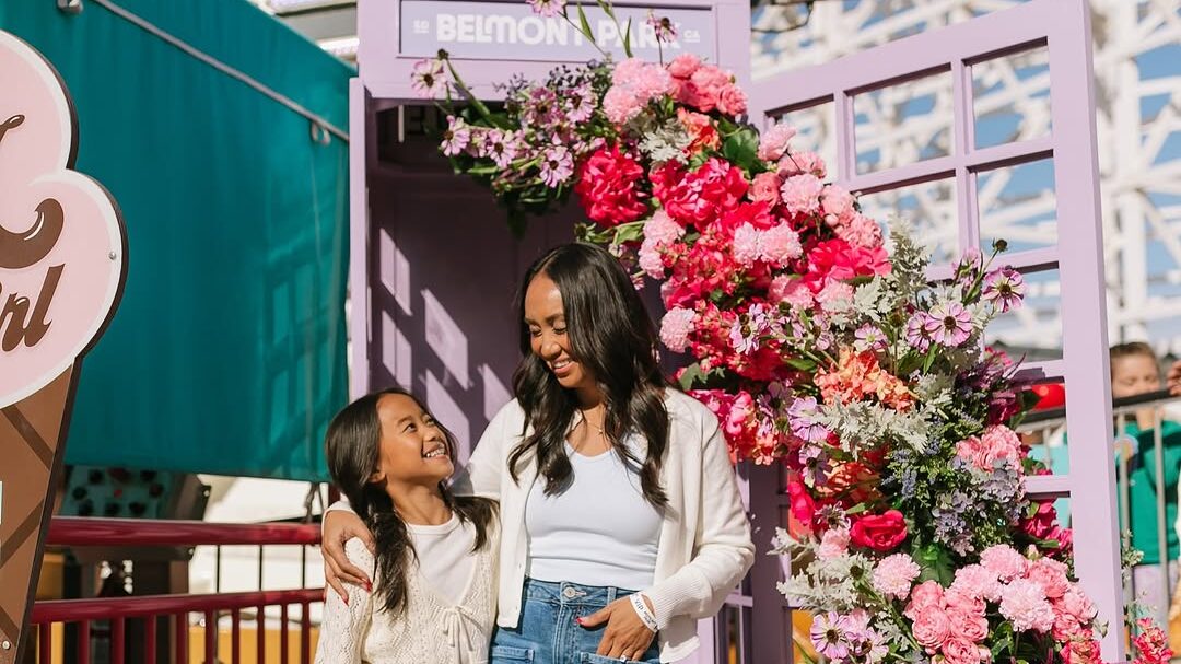 two girls standing in front of roller coaster at Belmont Park