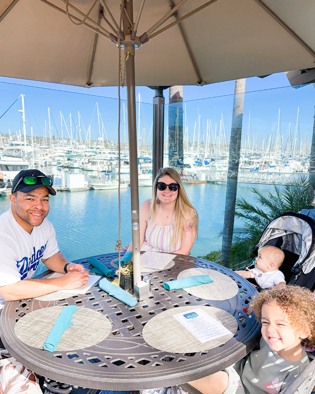 Family sitting at Blue Wave Bar & Grill outdoor seating in front of marina